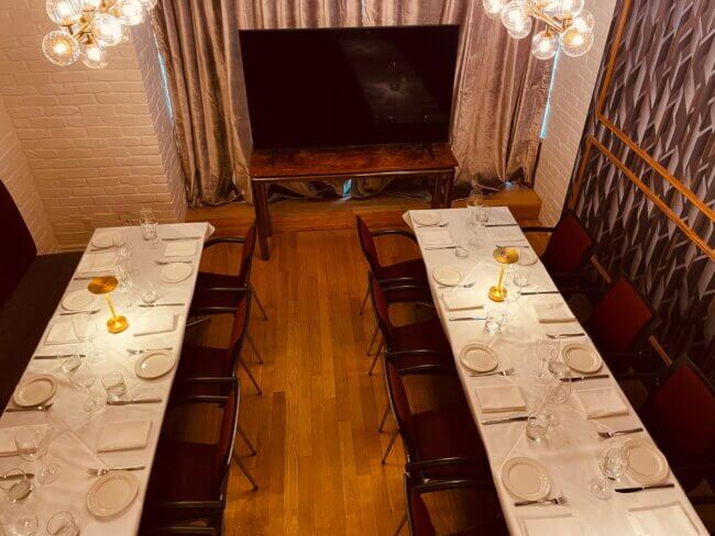 Stylish dining area with tables set for a gathering and a large screen.