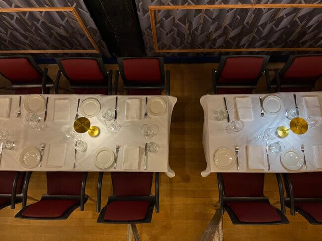 Overhead view of tables arranged with plates and glassware for dining.