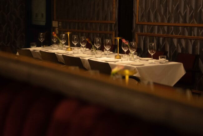 Cozy restaurant setting with tables set for dinner, visible through a reflective surface.