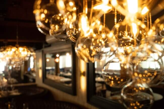 Warm, ambient lighting created by hanging glass pendant lights in an elegant restaurant.