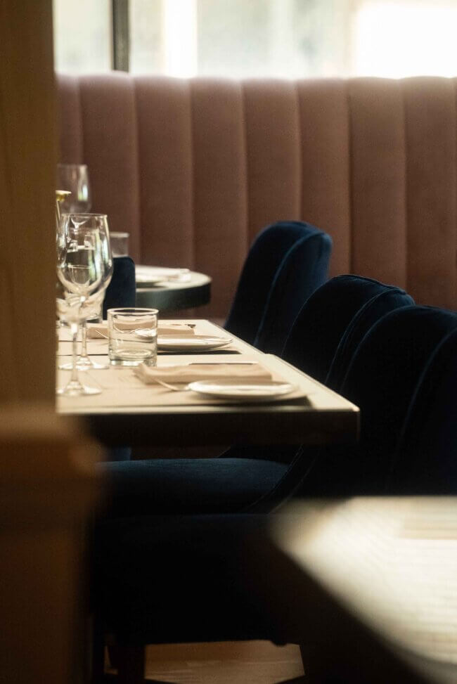 High-ceiling restaurant dining space with tall windows and contemporary decor.