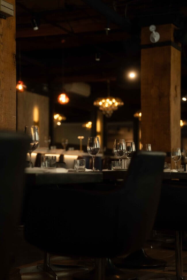 Elegant restaurant table set with glassware, illuminated by soft lighting.