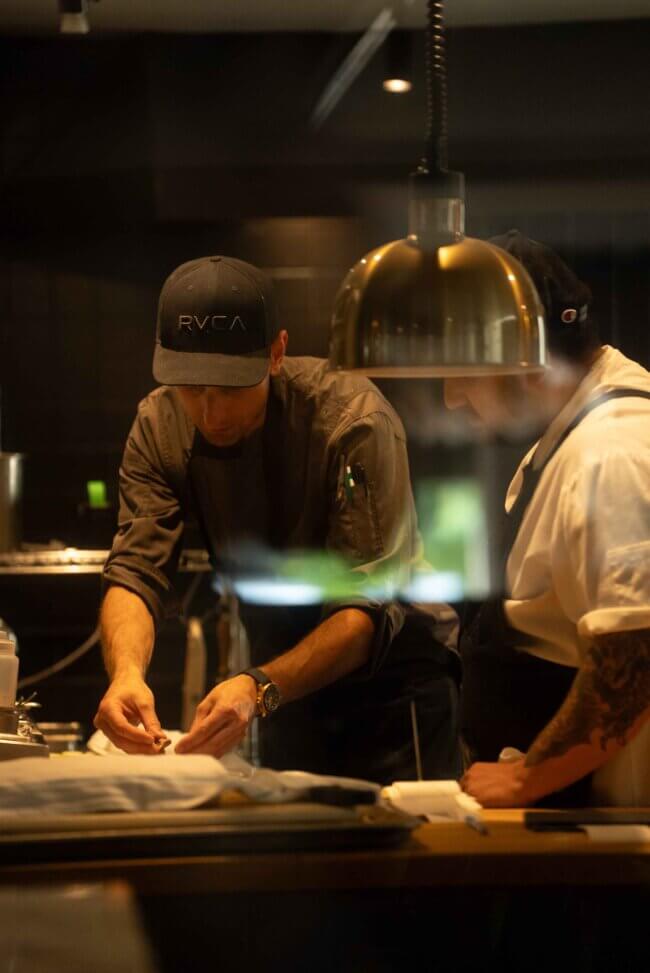 Two chefs focused on food preparation in a professional kitchen.