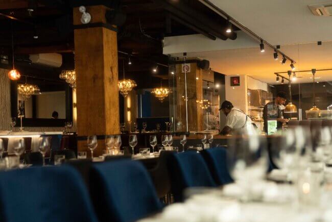 Restaurant terrace overlooking a cityscape, with tables and chairs aligned for al fresco dining.