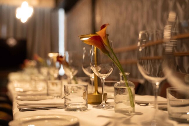 Elegant dining table set with glassware and a single flower at a restaurant.