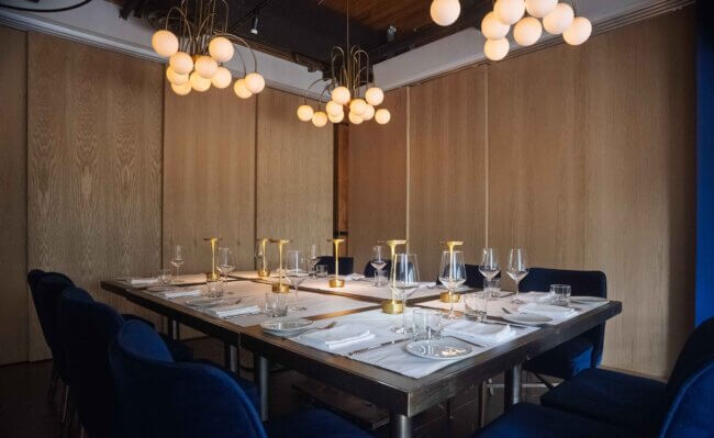 Elegant dining table set for a meal with blue chairs and modern lighting.