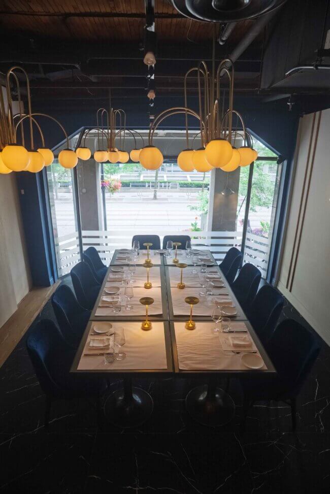 Overview of a long dining table with soft yellow pendant lights above.