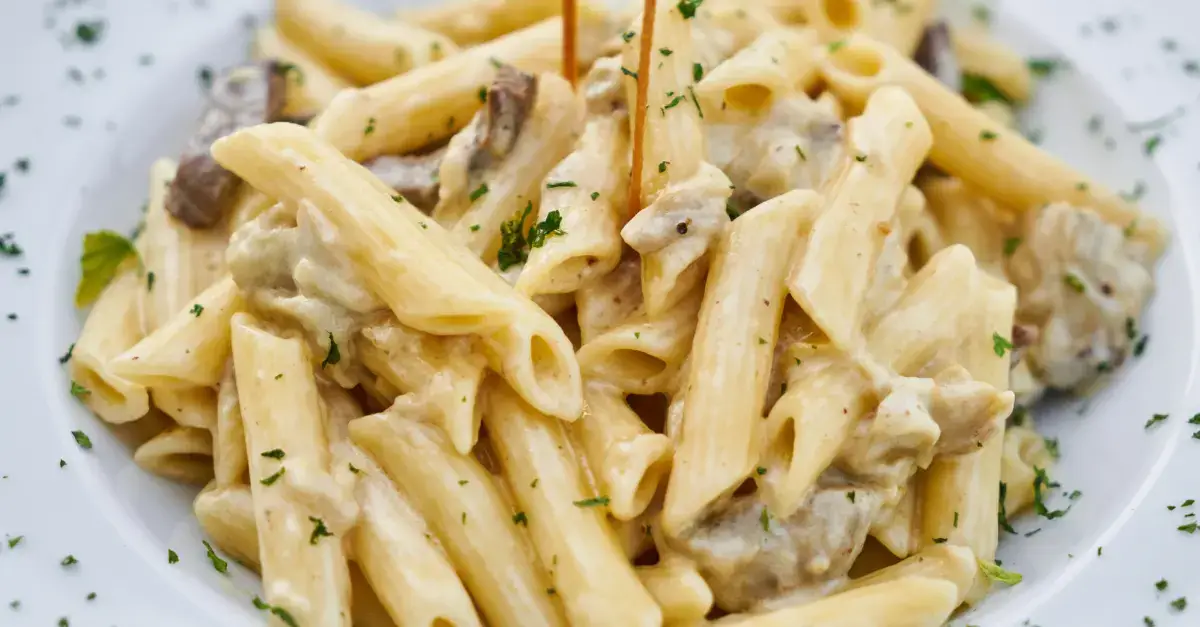 Penne pasta in a creamy Alfredo-style sauce with mushrooms, a perfect match for rich and indulgent pasta dishes.