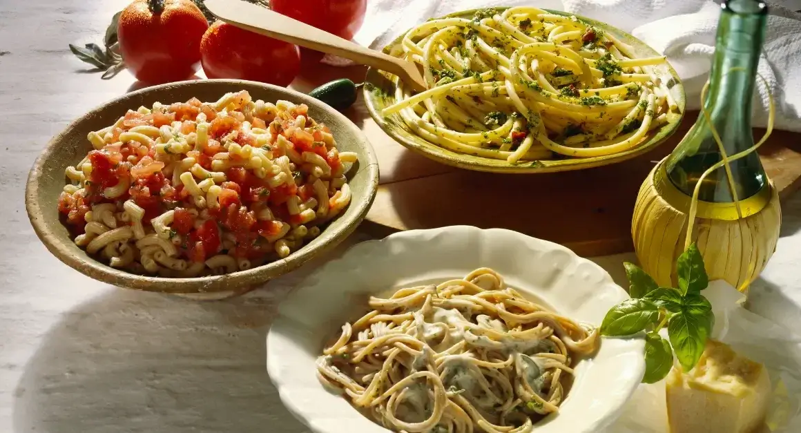 Assorted Italian pasta dishes including macaroni with tomato sauce, spaghetti with creamy sauce, and bucatini with pesto, perfect for pairing with their ideal sauces.