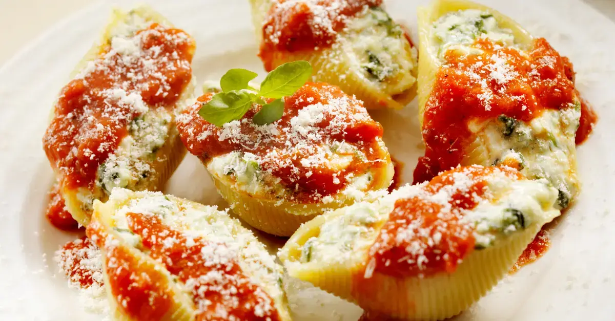 Pasta shells stuffed with ricotta cheese and spinach, topped with tomato sauce and Parmesan for a classic baked Italian pasta recipe.