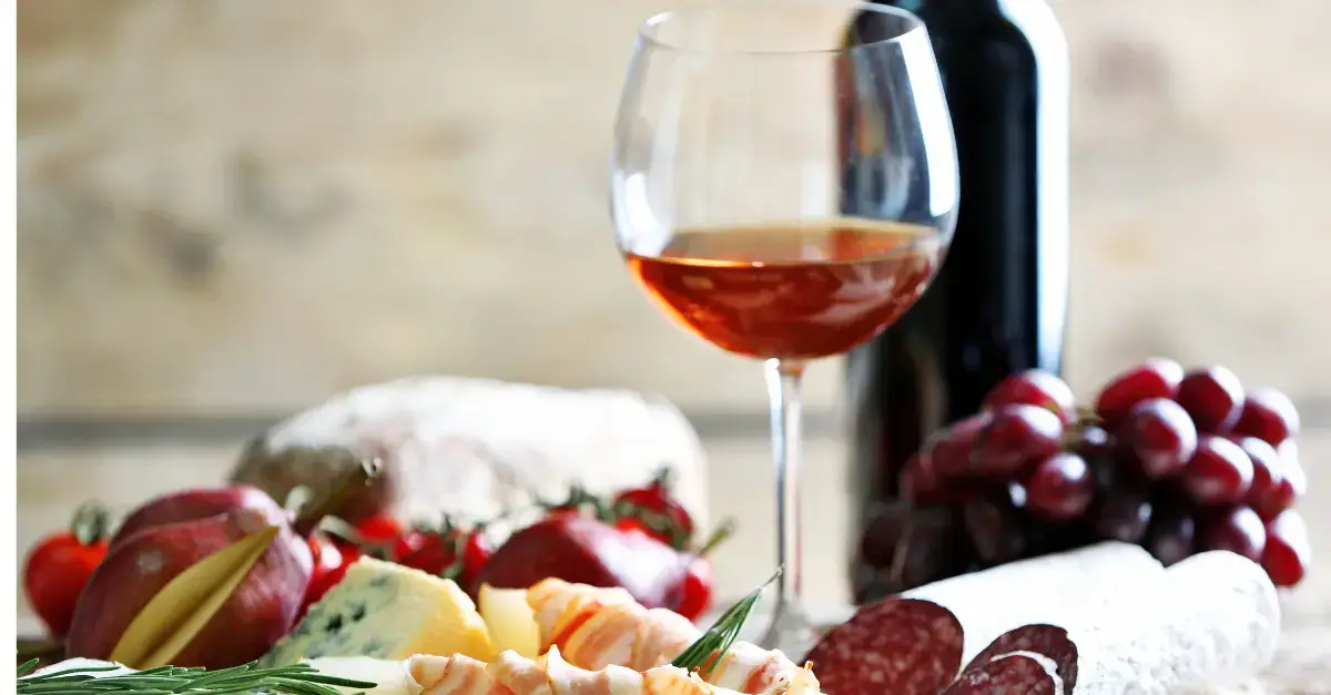 Italian charcuterie board with salami, cheese, grapes, and a glass of red wine, showcasing traditional food and wine pairings.