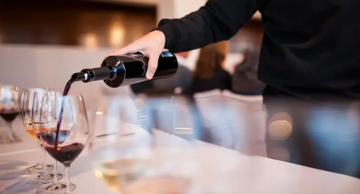 Sommelier pouring red wine into glasses during an Italian fine dining experience in downtown Toronto.