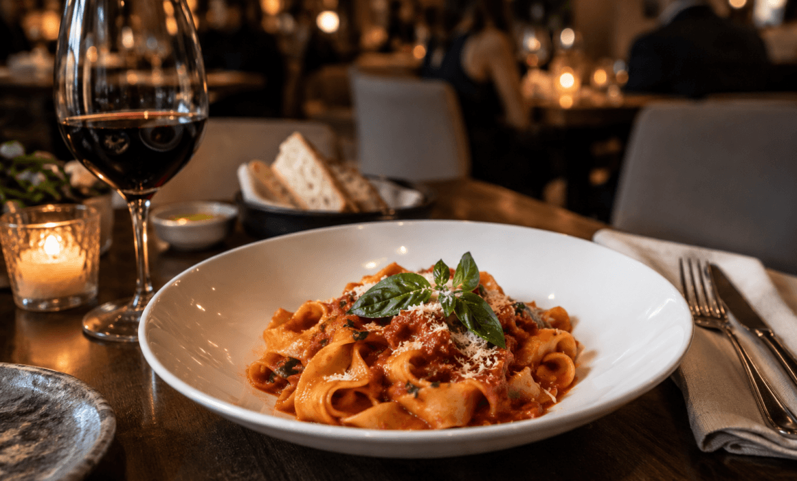 Fresh pasta with tomato sauce and basil served with red wine at an Italian restaurant in Toronto
